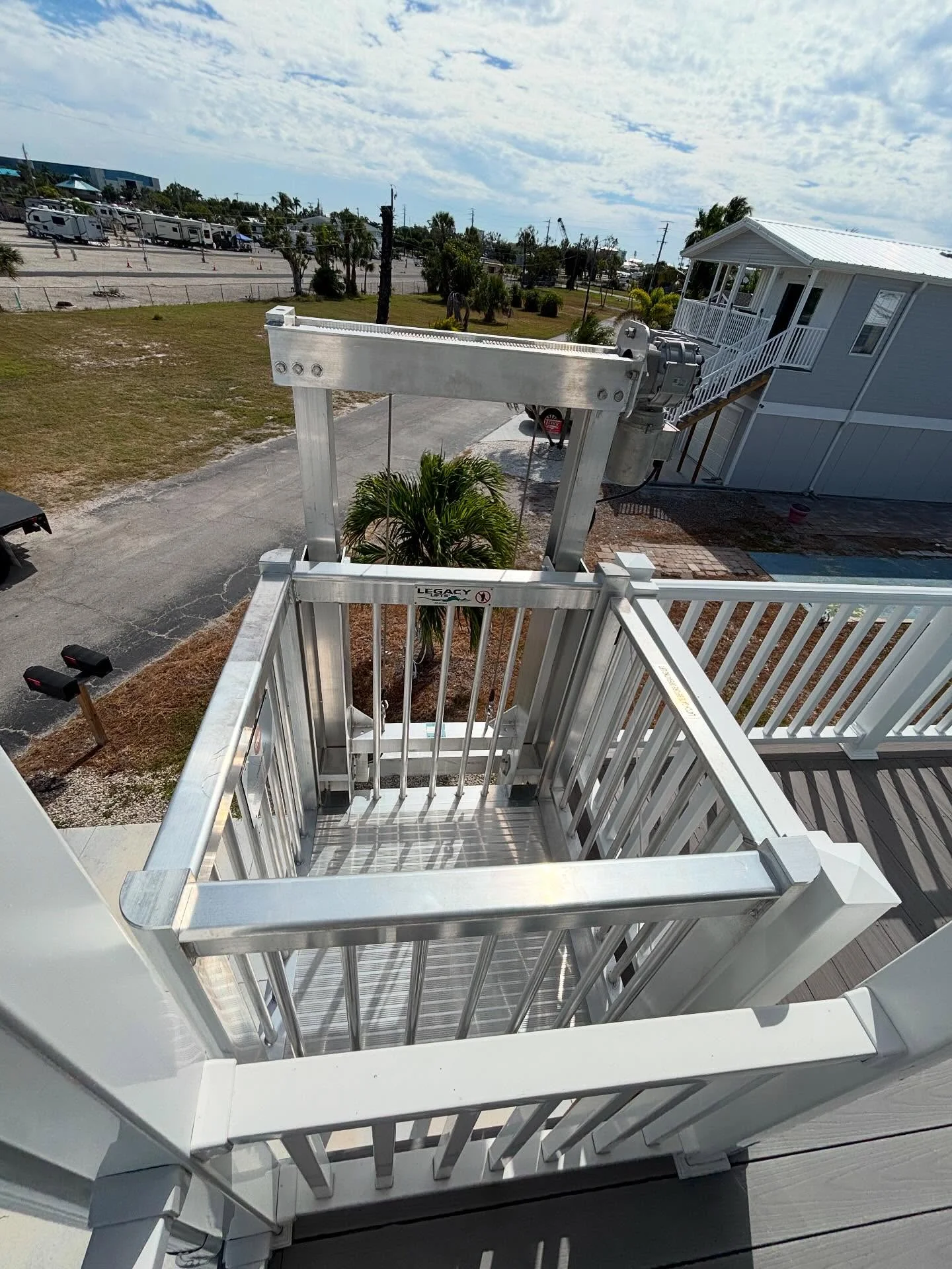 White aluminum cargo lift with safety gate and railings on residential deck